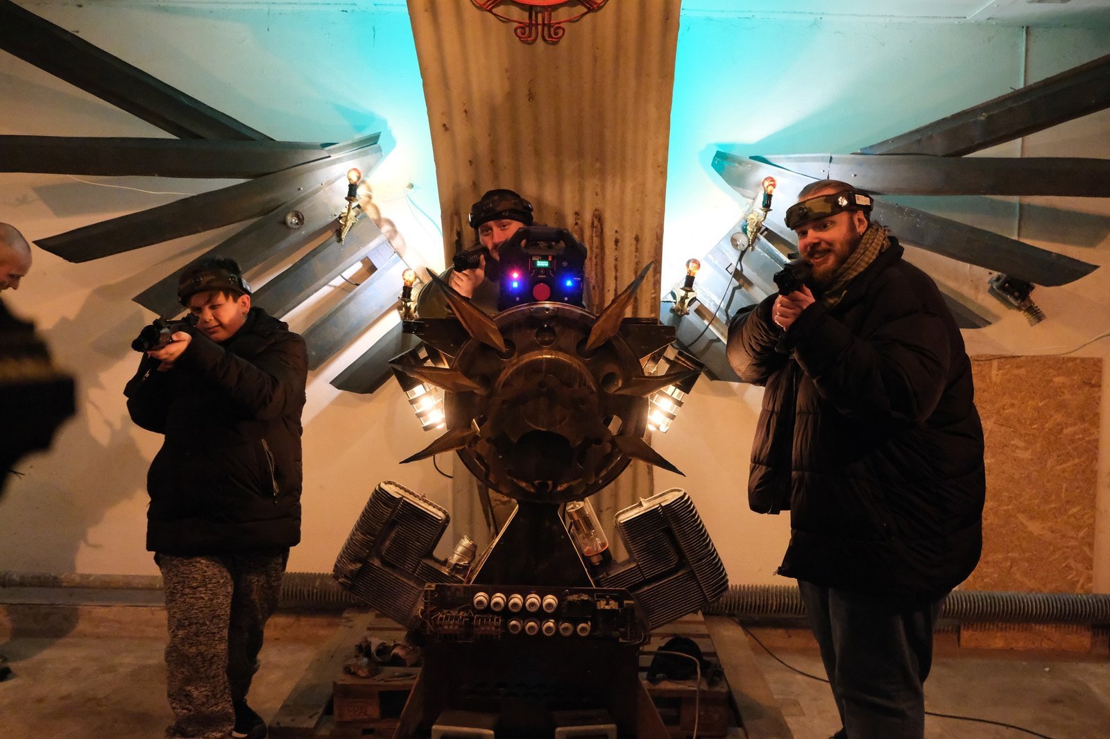 Deltagere med lasertag-udstyr foran en scenografisk installation i hallen
